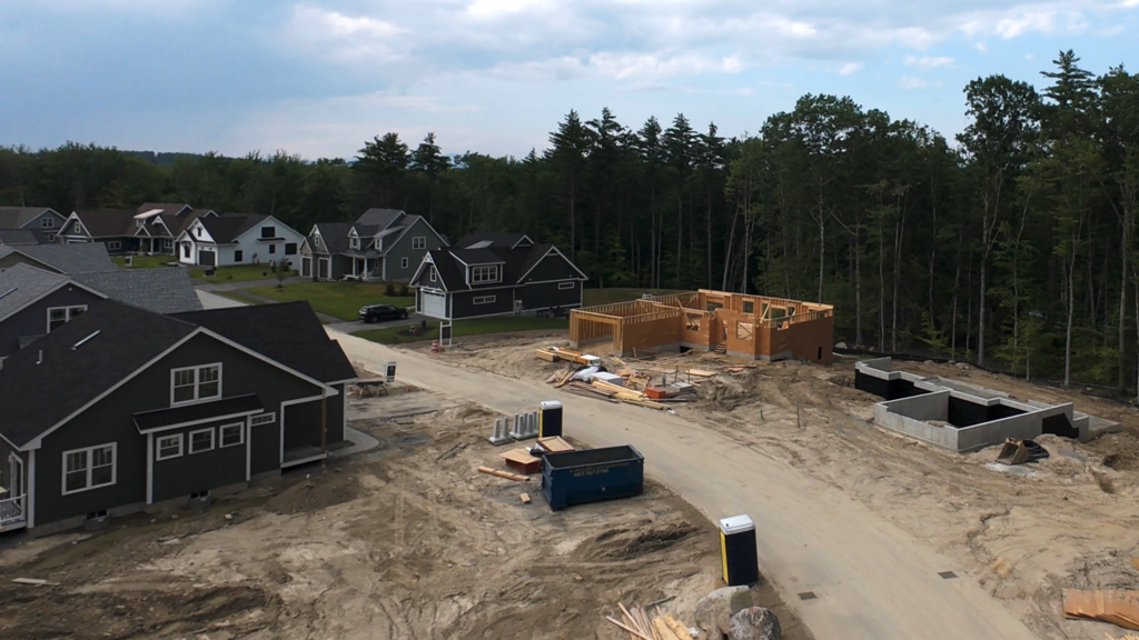 Aerial view of Lady of the Lakes Estates in Laconia, New Hampshire, showing completed homes alongside new homes under construction in the neighborhood.